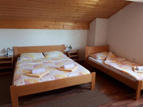 two beds in a room with wooden floors and wooden ceilings at House Jole in Drežnik Grad