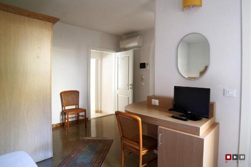 Habitación con escritorio, TV y espejo. en Albergo Giugni, en Prato