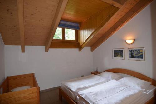 Bett in einem Schlafzimmer mit Holzdecke in der Unterkunft Ferienhäuser "In der Waldperle" in Bischofsmais