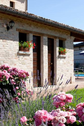 a stone house with flowers in front of it at Parco Ducale Country House in Urbania