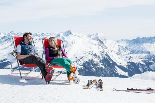 a man and a woman sitting in chairs in the snow at Die Monika Aparthotel in Gaschurn
