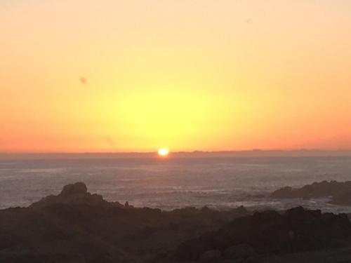 a sunset over the ocean with the sun in the sky at Golden Tower in Iquique
