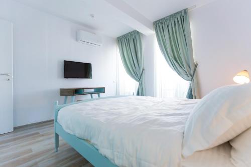 a bedroom with a white bed with a television and curtains at The Shore House in Mamaia Nord