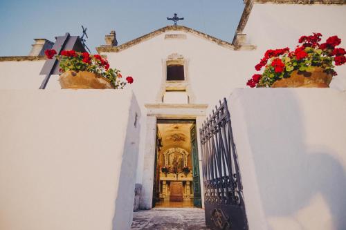 a church with white walls and flowers inront of it at Masseria Luco in Martina Franca