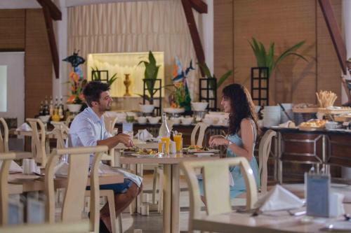 a man and woman sitting at tables in a restaurant at Bandos Maldives in North Male Atoll