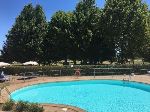 a large blue swimming pool with trees in the background at Le Macerine in Castiglione del Lago