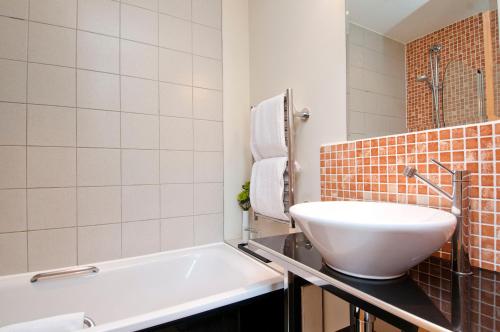 a bathroom with a sink and a bath tub at Grand Plaza Serviced Apartments in London