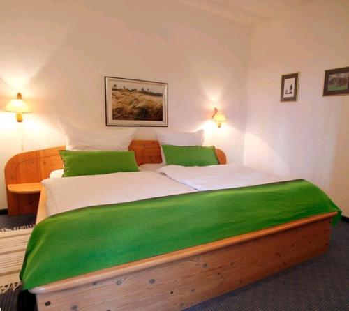 Un dormitorio con una gran cama de madera con sábanas verdes en Landhaus Ostseeblick en Kronsgaard