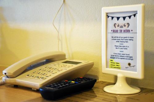 a phone sitting on top of a desk next to a monitor at TUCK Me iN in Chiang Mai