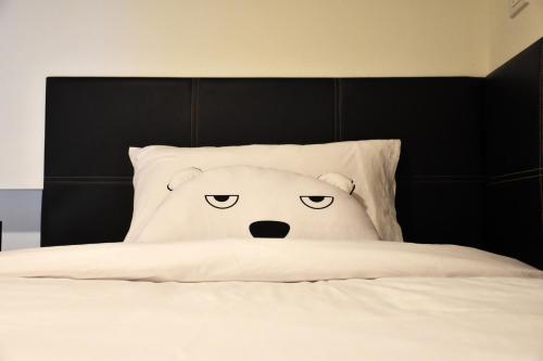 a pillow with an angry face on a bed at TUCK Me iN in Chiang Mai