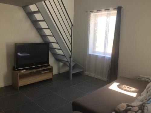 uma sala de estar com uma televisão e uma escada em Au bon logis Luberon 50m2 em Cheval-Blanc
