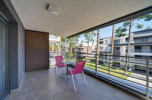 einen Balkon mit rosa Stühlen, einem Tisch und einem großen Fenster in der Unterkunft Komfortowe Apartamenty Sun Seasons 24 w Pogorzelicy Blisko Morza by Noclegi Renters in Pogorzelica