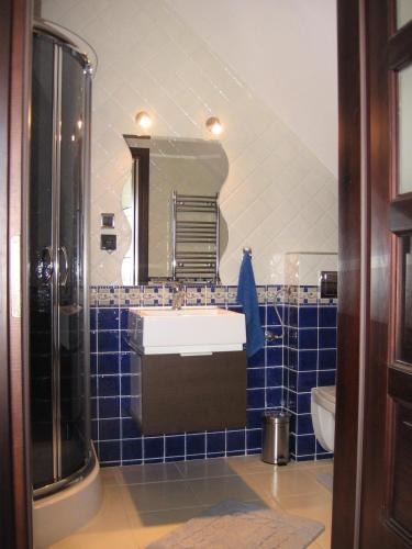 a blue tiled bathroom with a sink and a mirror at Domki pokoje pod Wierzba in Sarbinowo