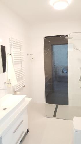 a white bathroom with a mirror and a sink at Apartament Muszelka in Ustka