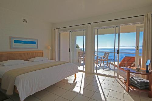 a bedroom with a bed and a balcony with the ocean at Roman Rock Apartments in Simonʼs Town