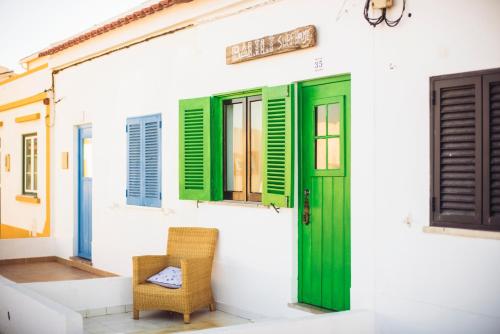 a house with green shutters and a chair at Balili Surf House in Baleal