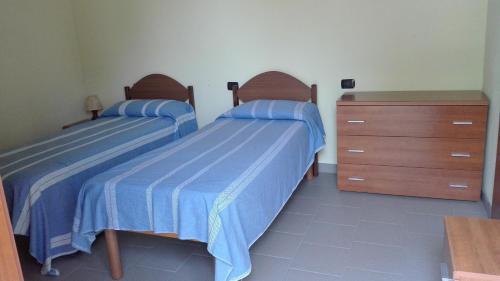 two beds in a bedroom with blue sheets and a dresser at Locanda Lago Bleu in Pellegrino Parmense