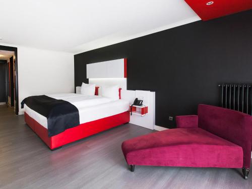 Habitación de hotel con cama y silla en DORMERO Hotel Freudenstadt en Freudenstadt