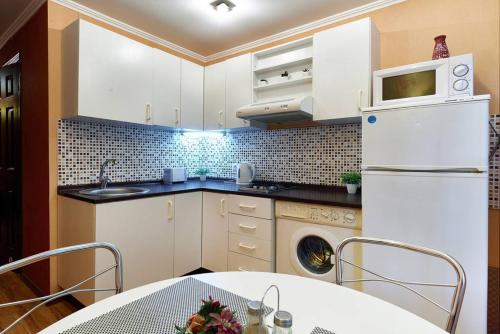 a kitchen with white cabinets and a white refrigerator at Home Hotel Apartments on Kontraktova Ploshcha in Kyiv
