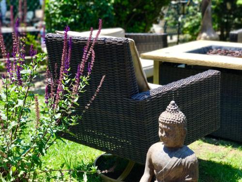 a statue next to a wicker chair in a garden at Kenny's Tipperary Inn in Montauk