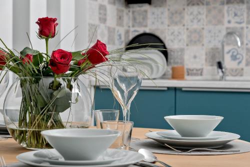 a table with red roses in a vase and plates at Villa Kozina in Podstrana