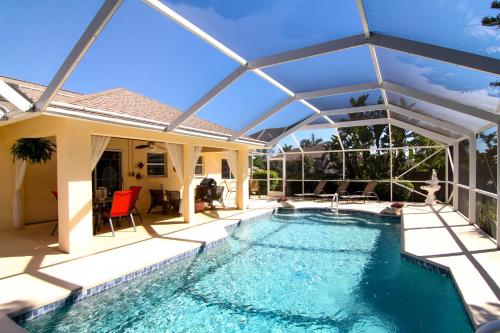 a swimming pool with an umbrella over a house at Villa Joella in Cape Coral
