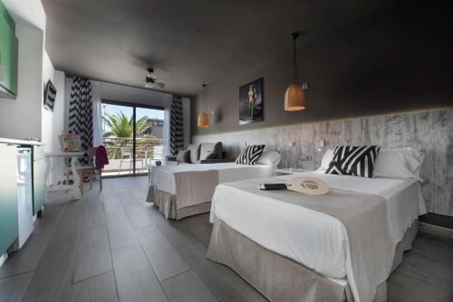 a hotel room with two beds and a living room at Aparthotel Vibra Mogambo - Adults only in Playa d'en Bossa