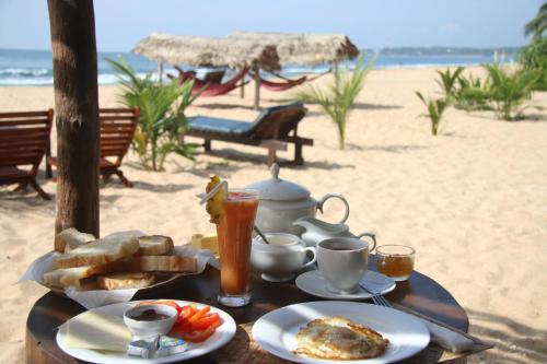 a table with food and drinks on the beach at Shiva's Beach Cabanas in Tangalle