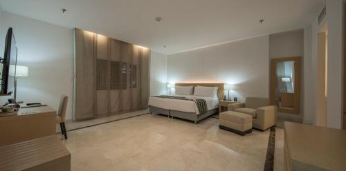 a bedroom with a bed and a chair in a room at Hotel Dann Carlton Barranquilla y Centro de Convenciones in Barranquilla