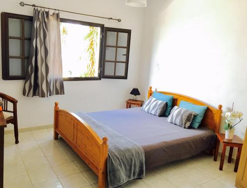 a bedroom with a bed with blue pillows and a window at La Santa Feel Good in La Santa