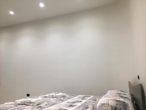 a bed in a room with a white wall at B&B Vittorio Emanuele in Licata