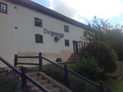 a white building with a sign on the side of it at The George Great Oxendon in East Farndon