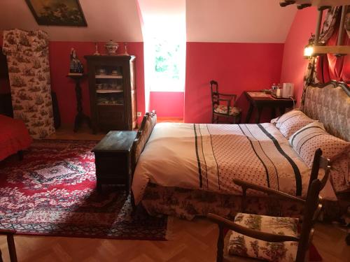 a bedroom with a bed and a red wall at Résidence La Beauceronne in Ouarville