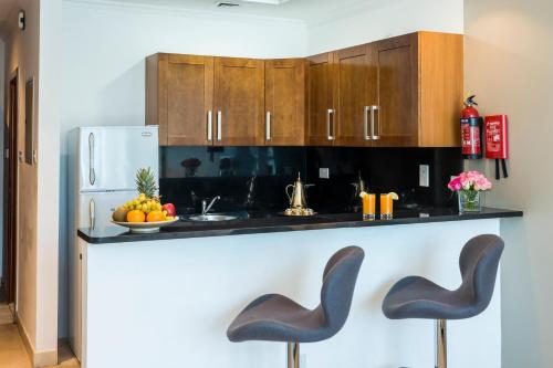a kitchen with a counter with two black stools at Jannah Marina Hotel Apartments in Dubai