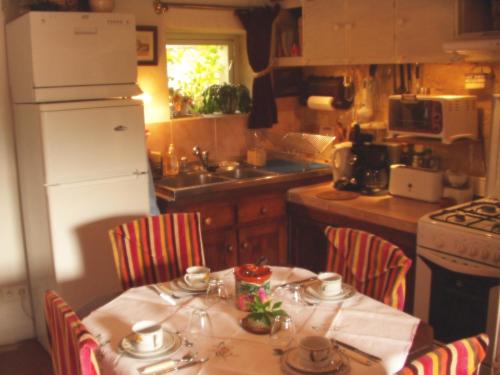a kitchen with a table and chairs with a white refrigerator at Gîte de La Galaisière in Préaux
