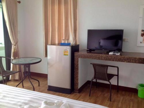 a room with a refrigerator and a table and a tv at Dusita Residence ดุสิตา เรสซิเดนซ์ in Phetchabun