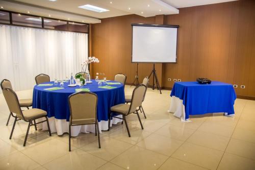 a conference room with blue tables and chairs and a screen at Hotel y Restaurante El Guarco in Cartago
