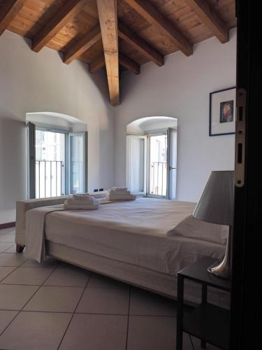 a bedroom with a large bed with two windows at Appartamenti al Golfo in Salò