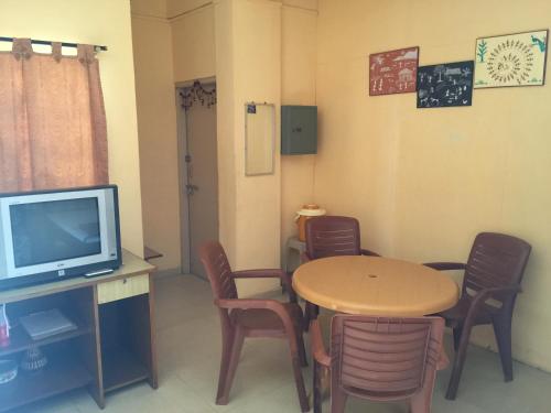 a room with a table and chairs and a television at MTDC Approved Mohiniraj Guest House in Nashik