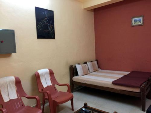 a bedroom with a bed and two red chairs at MTDC Approved Mohiniraj Guest House in Nashik