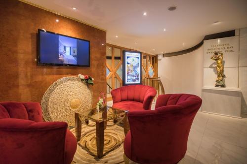 a waiting room with red chairs and a flat screen tv at Amman International Hotel in Amman