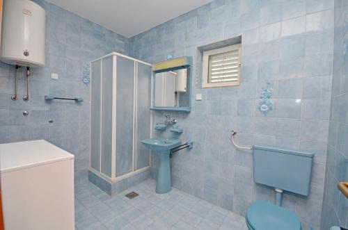a blue bathroom with a sink and a toilet at Apartments Vila Punta in Jadrtovac