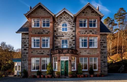 a large brick house with a green door at Duisdale House Hotel in Isleornsay