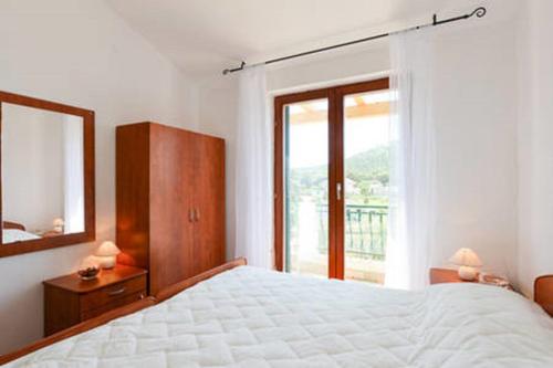 a bedroom with a bed and a mirror and a window at Apartments Pero in Zapuntelo