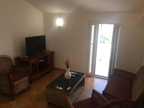 een woonkamer met een tv en stoelen en een tafel bij Apartments SIM in Budva