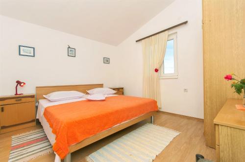 ein Schlafzimmer mit einem orangenen Bett und einem Fenster in der Unterkunft Apartments Srdan in Rogoznica