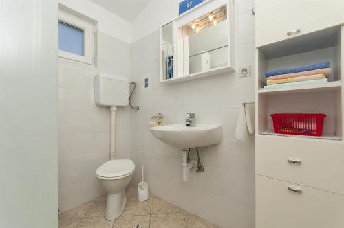 ein weißes Bad mit einem WC und einem Waschbecken in der Unterkunft Apartments Srdan in Rogoznica