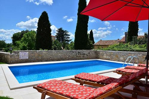 a swimming pool with two chairs and a red umbrella at Villa Letizia in Oprtalj