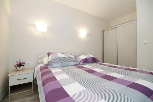 a bedroom with a purple and white bed and a nightstand at Apartment Andelina in Split