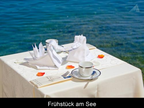 a white table with a cup and napkin and a teaucer at Hotel-Restaurant "Veldener Traumschiff" direkt am See in 2min im Zentrum in Velden am Wörthersee
